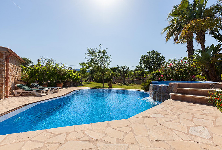 Poolterrasse Sonnenliegen Rasen Natursteinmauer Palmen