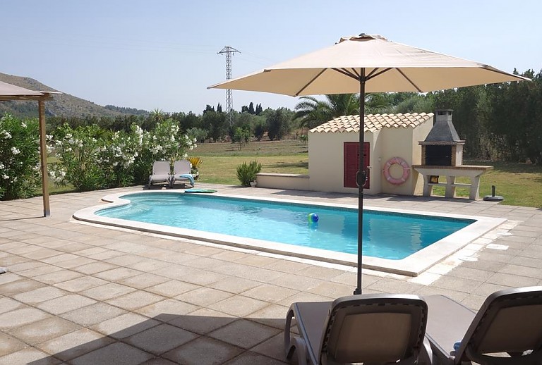 Pool Terrasse Sonnenschirm Gartenmöbel Büsche Rasen Berg