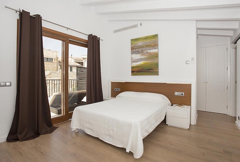 Schlafzimmer mit Doppelbett und großen Fenstern