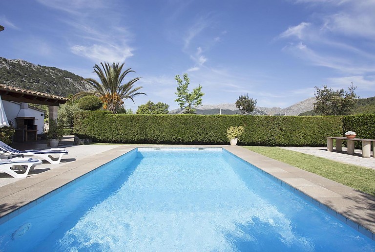 Pool mit Sonnenliegen unter blauem Himmel