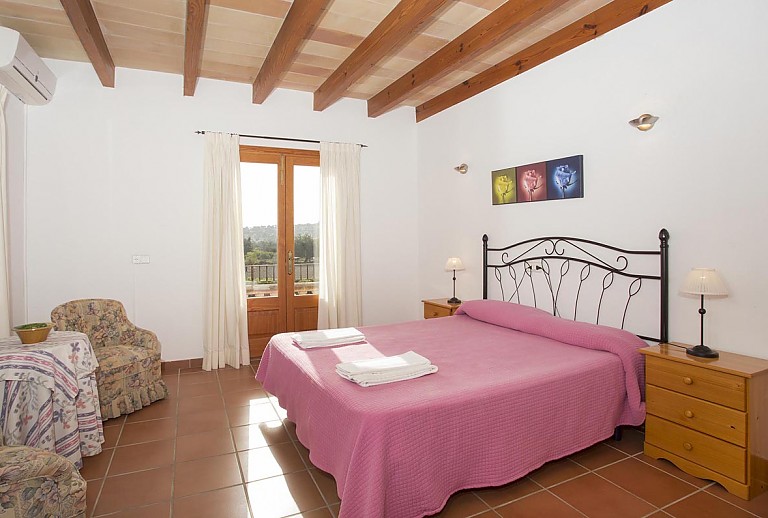 Doppelbett im Schlafzimmer mit Tür zum Außenbereich