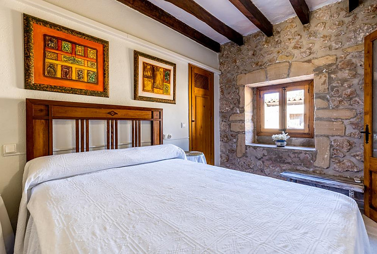 Schlafzimmer mit Doppelbett Natursteinwand und Fenster