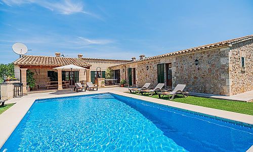 Poolbereich vor der Finca mit Rasenfläche und Sonnenliegen