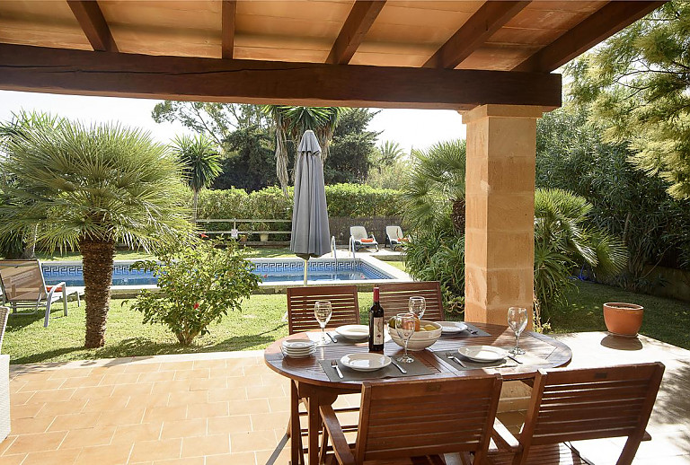Poolblick von der Terrasse mit Vordach und Gartenmöbeln