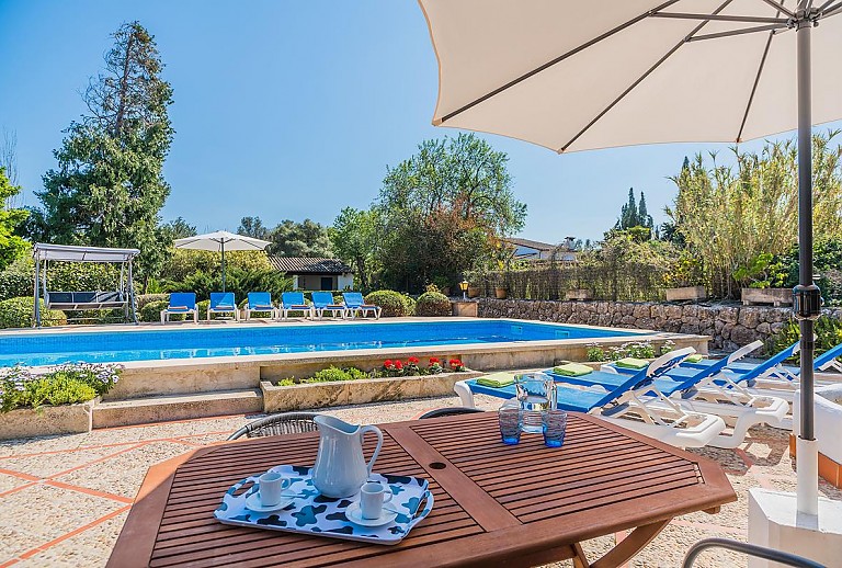 Sonnenschirm am Poolbereich vor der Finca mit Sonnenliegen