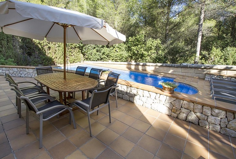 Esstisch mit Stühlen und Sonnenschirm am Pool