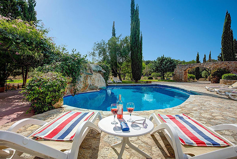 Poolbereichmit Sonnenliegen vor der Finca auf dem Grundstück mit Bäumen