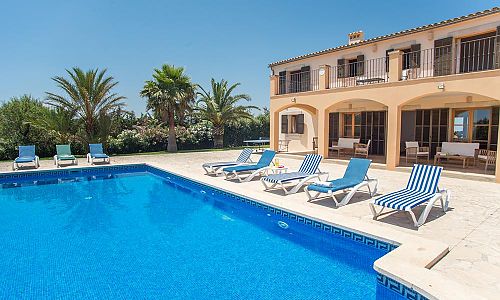 Poolbereich vor der Finca mit Sonnenliegen und Palmen