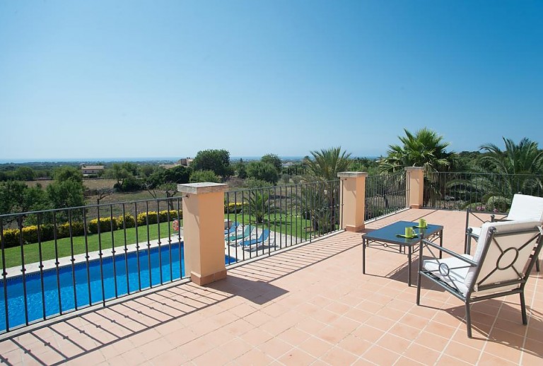 Terrasse mit Sesseln und Poolblick