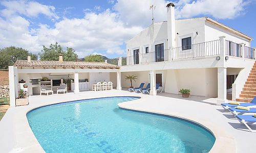 Poolbereich mit Liegestühlen vor dem Ferienhaus