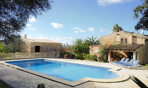 Poolbereich mit Poolliegen vor der Natursteinfinca