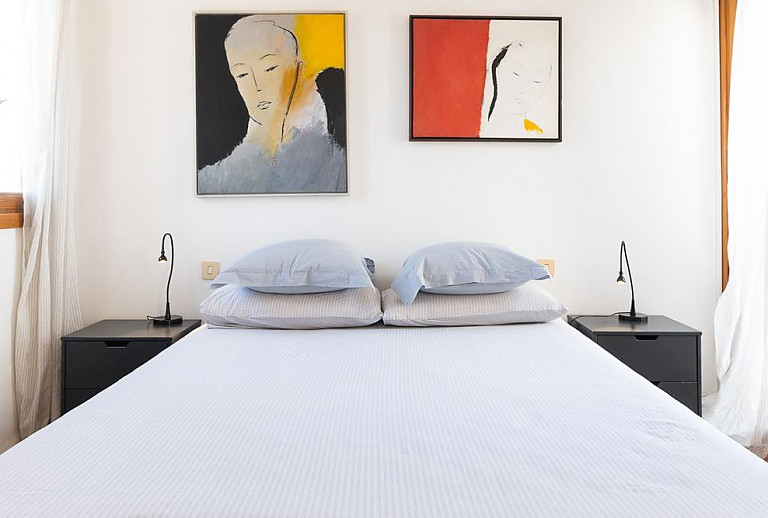 Schlafzimmer mit Doppelbett und Wandbildern
