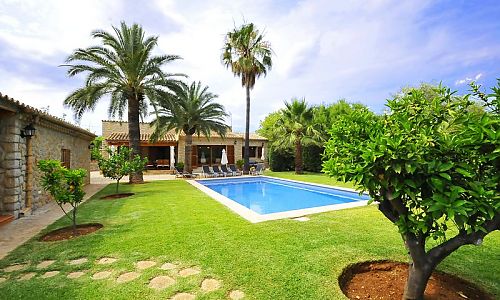 Rasenfläche und Palmen am Pool vor der Finca