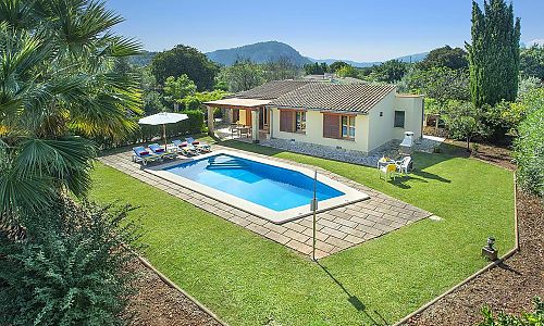 Pool mit Rasenfläche und Sonnenliegen vor Finca