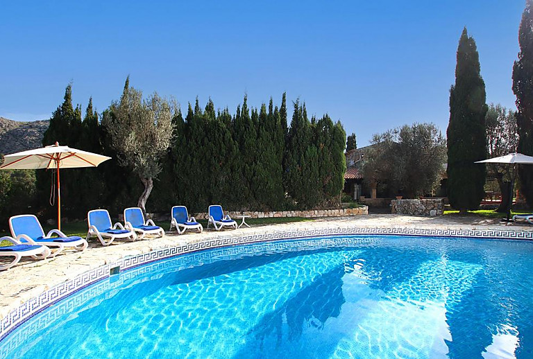 Pool mit Sonnenschirm und Liegen vor der Finca