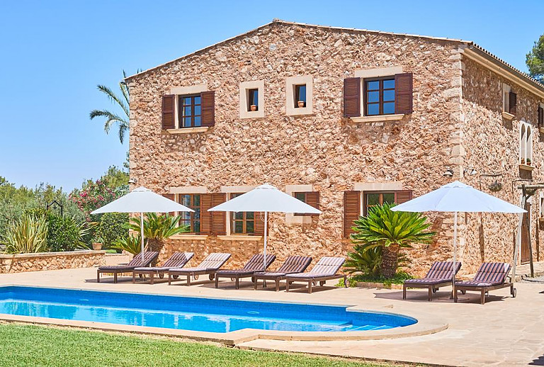 Pool mit Rasen und Sonnenliegen vor der Finca