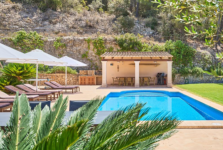 Pool mit Rasen und Sonnenliegen vor der Finca