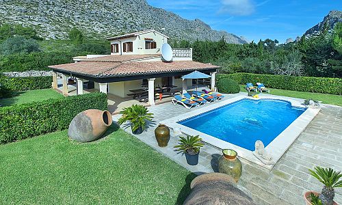 Poolbereich mit Sonnenliegen und Topfpflanzen vor der Finca