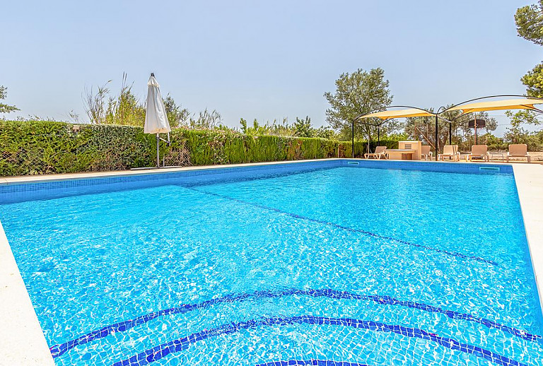 Sonnenliegen und Sonnensegel am Poolbereich