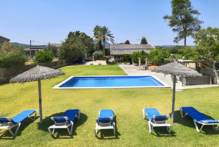 Garten mit Sonnenliegen auf dem Rasen am Pool