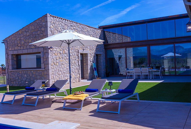 Sonnenliegen und Sonnenschirm auf der Terrasse am Pool