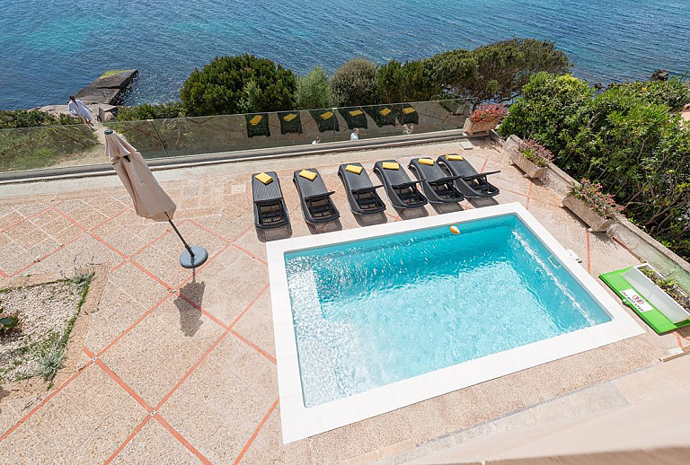 Poolterrasse mit Sonnenliegen und Sonnenschirm