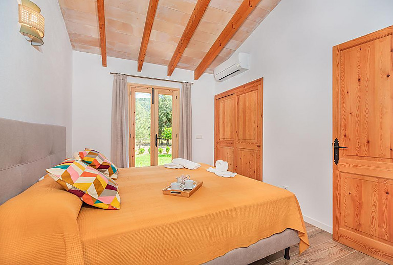 Schlafzimmer mit Doppelbett und Zugang zum Garten