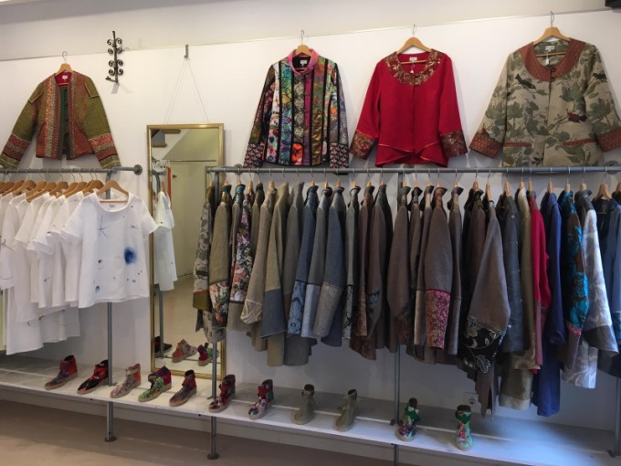 Boutiquewand mit Kleiderständern, Spiegel, Jacken und Schuhen